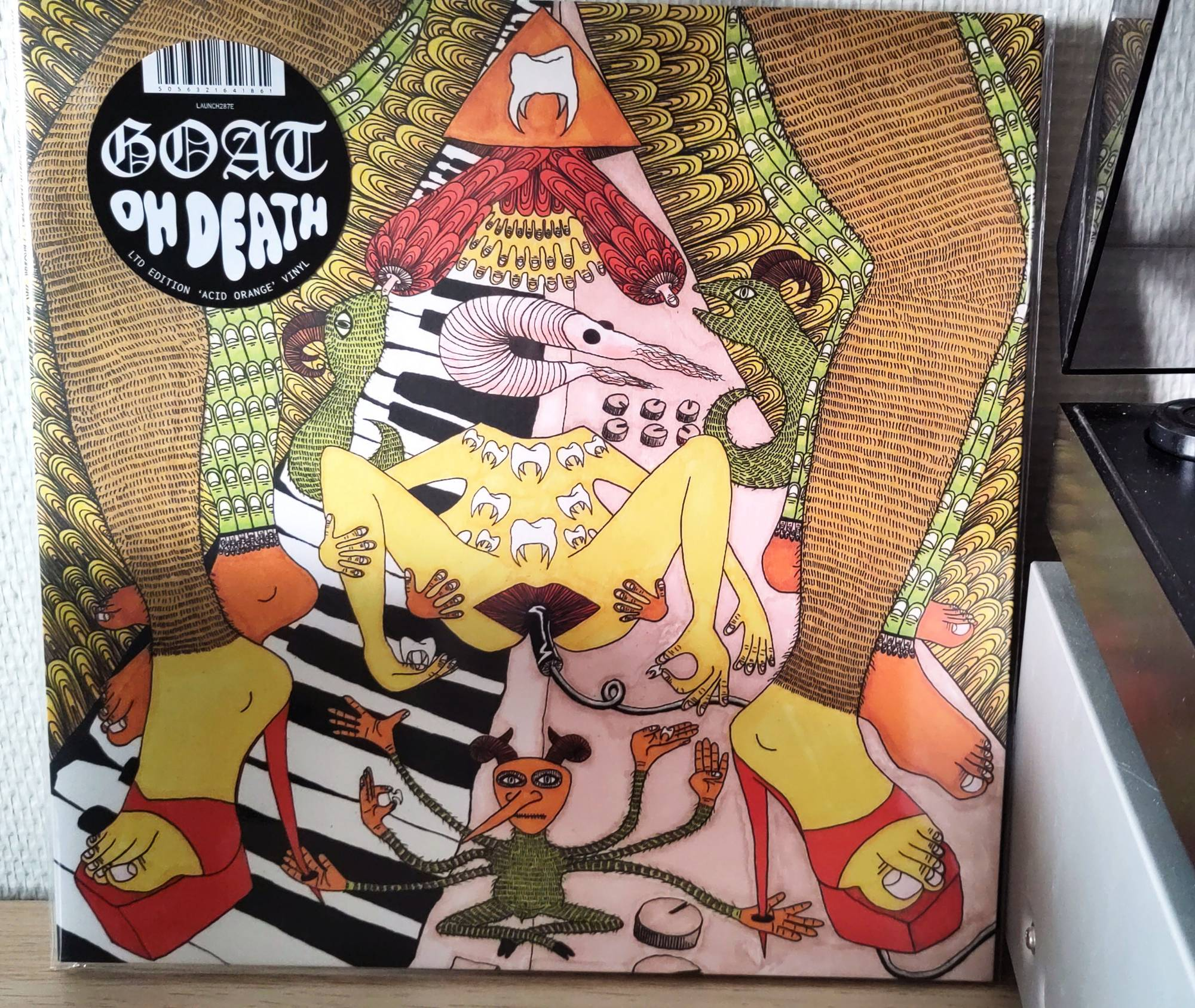 The album cover is a sprawling, psychedel-ish line drawing painted in bright colours. It's placed against the wall next to my record player.