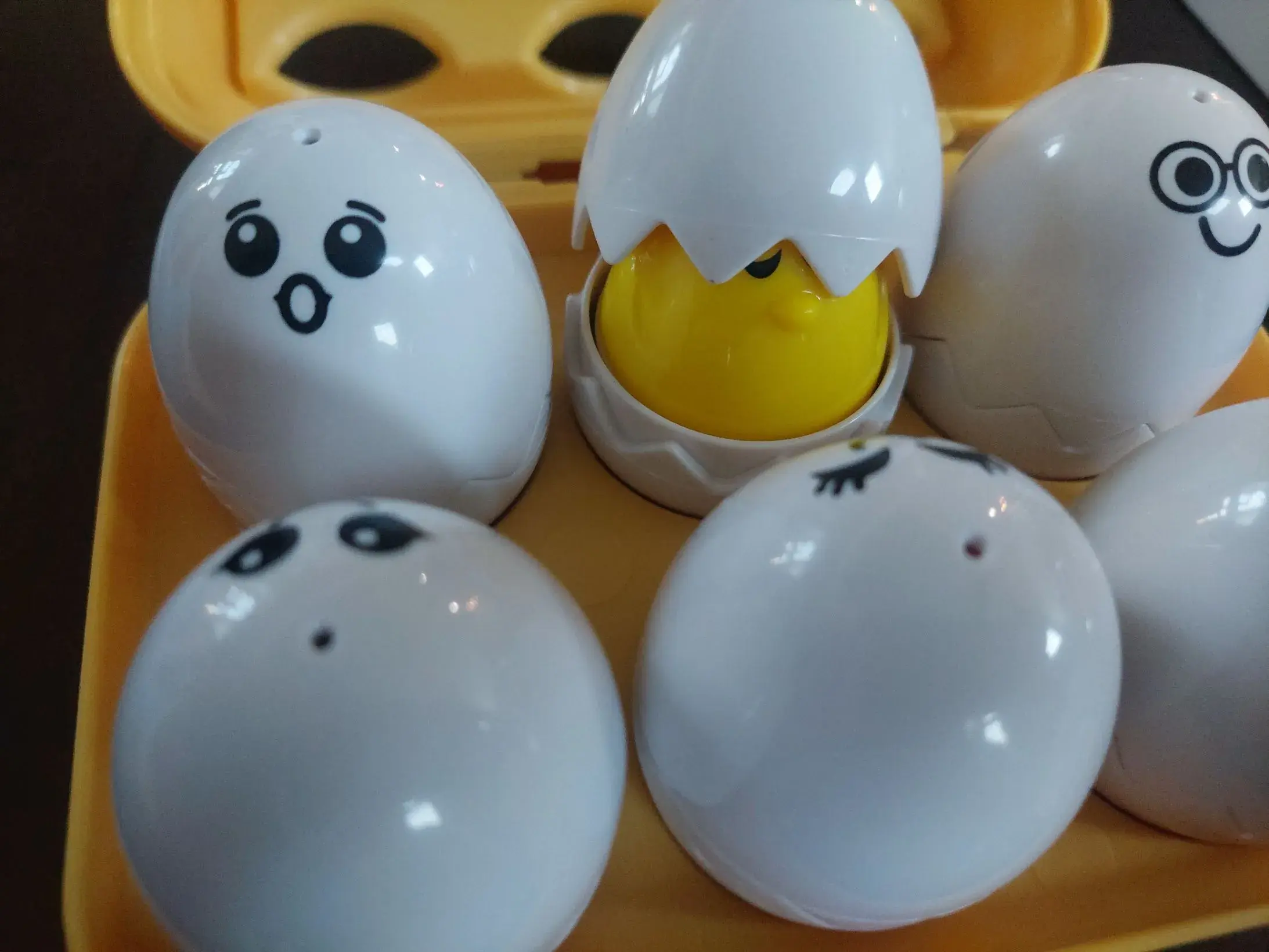 A kids toy that a carton of six toy eggs with faces. The top left one is pogging.