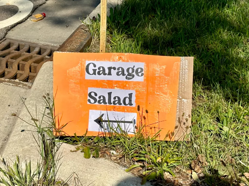 A sign beside a road that reads “Garage Salad” and features an arrow pointing left